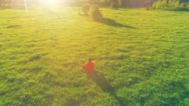 Vol radial à basse altitude au-dessus du yoga sportif homme à l'herbe verte parfaite. Coucher de soleil en montagne. — Video