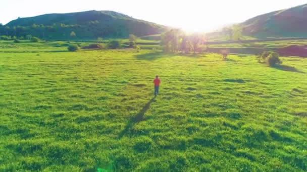 Vlucht over sport man op perfect groen gras weide. Zonsondergang in de bergen — Stockvideo