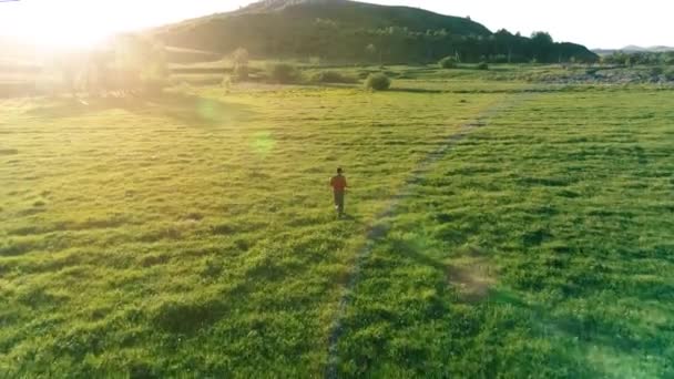 Vlucht over sport man op perfect groen gras weide. Zonsondergang in de bergen — Stockvideo