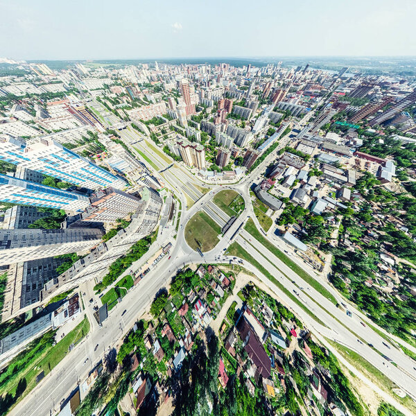 Aerial city view with crossroads and roads, houses, buildings, parks and parking lots. Sunny summer panoramic image