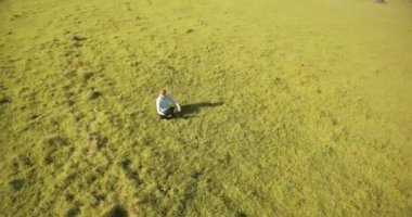 UHD 4k havadan görünümü. Defter pad ile yeşil çim sahasında oturan işadamı üzerinde düşük yörünge uçuş