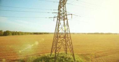 Yüksek voltajlı elektrik kulesi ve yeşil ve sarı alandaki elektrik hatları yakınında dikey hareket.
