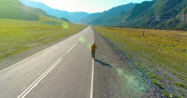 Voo de baixa altitude atrás de homem desportivo na estrada de asfalto perfeito — Vídeo de Stock