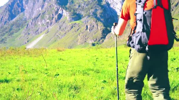 Sırt çantası ile yeşil dağ çayır üzerinde yürüyen adam hiking. Yaz spor ve eğlence kavramı. — Stok video