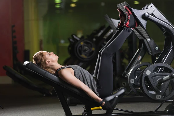 Sportliche Frau mit Hantelpresse für Beine. Fitnessstudio. — Stockfoto