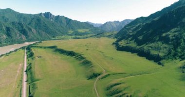 Güneşli yaz sabahında havadan kırsal dağ yolu ve çayır. Asfalt karayolu ve nehir.
