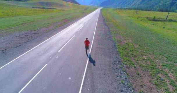 Low altitude flight in front of sporty man at perfect asphalt road — Stock Video
