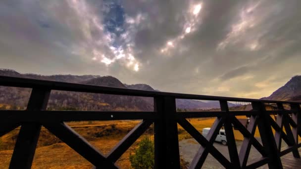 Timelapse van houten hek op hoog terras bij berglandschap met wolken. Horizontale schuifbeweging — Stockvideo