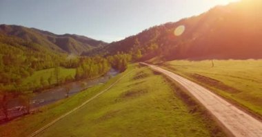 Güneşli yaz sabahında taze dağ nehri ve çayır üzerinde uçuşun ortasında. Aşağıdaki kırsal toprak yol.