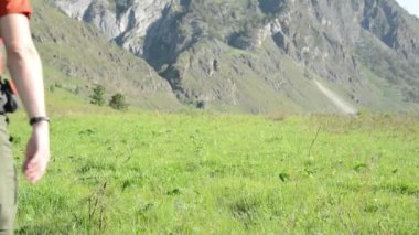 Sırt çantası ile yeşil dağ çayır üzerinde yürüyen adam hiking. Yaz spor ve eğlence kavramı.