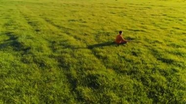 Yeşil çimlerde spor yogacısı üzerinde alçak irtifa radyal uçuş. Dağda gün batımı.