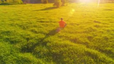 Yeşil çimlerde spor yogacısı üzerinde alçak irtifa radyal uçuş. Dağda gün batımı.