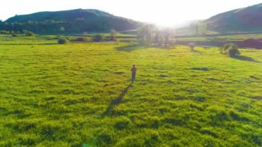 Mükemmel yeşil çayır üzerinde uçan bir sporcu. Dağda gün batımı
