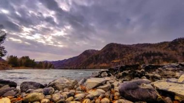 Zaman atlamalı bir nehir dağ orman kenarında bir kadeh. Büyük kayalar ve hızlı bulutlar movenings. Yatay kaydırıcı hareket