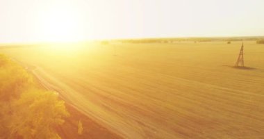 UHD 4K hava görüntüsü. Sarı kırsal alan ve toprak yol üzerinde orta-uçuş