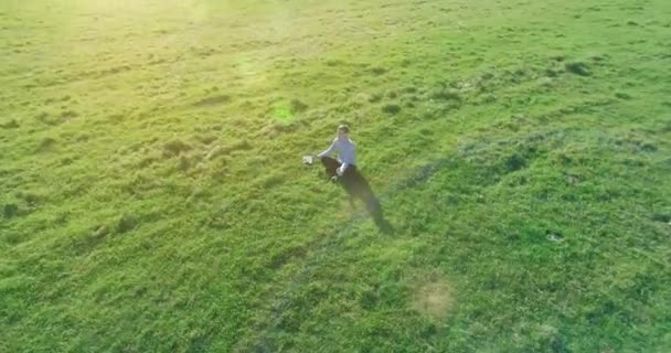 Lage baanvlucht rond mens op groen gras met notitieblok op geel landelijk veld. — Stockvideo