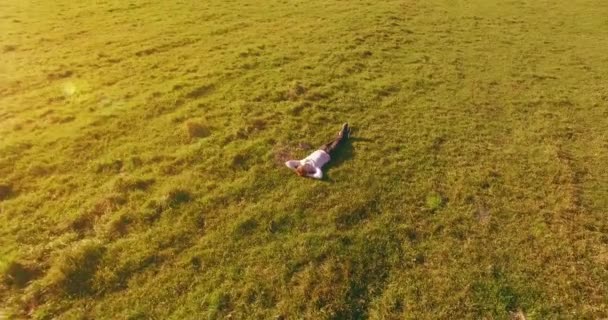 Lage baanvlucht rond mens op groen gras met notitieblok op geel landelijk veld. — Stockvideo
