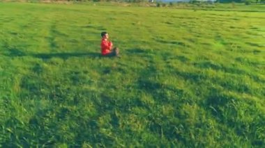 Yeşil çimlerde spor yogacısı üzerinde alçak irtifa radyal uçuş. Dağda gün batımı.