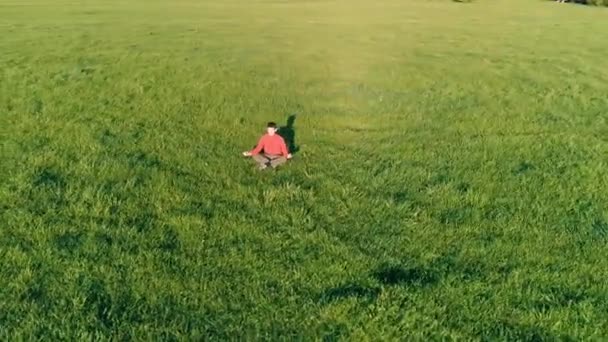 Lage hoogte radiale vlucht over sport yoga man op perfect groen gras. Zonsondergang in de bergen. — Stockvideo