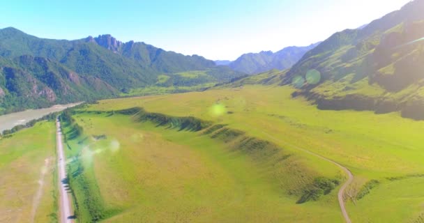 Luchtfoto landelijke bergweg en weide op zonnige zomerochtend. Asfaltweg en rivier. — Stockvideo