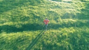 Uçuş mükemmel yeşil çim kırsal çayır offroad koşan sportif adam üzerinde. Günbatımı dağ