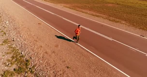 Vuelo de baja altitud frente al deportista en el camino perfecto de asfalto — Vídeo de stock