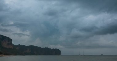 Kumsalda ve teknelerle deniz manzarasında yağmur bulutları hızlanıyor. Okyanusta tropik fırtına.