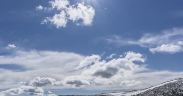Tidsförskjutning av molnlandskap bakom bergstoppen. Snö, stenar, klippor och djupblå himmel. Hög höjd. — Stockvideo