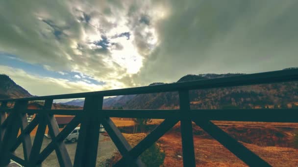 Timelapse van houten hek op hoog terras bij berglandschap met wolken. Horizontale schuifbeweging — Stockvideo