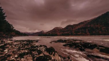 Dağ ormanı yakınlarındaki bir nehrin hızlandırılmış görüntüsü. Büyük kayalar ve hızlı bulutlar hareket ediyor..
