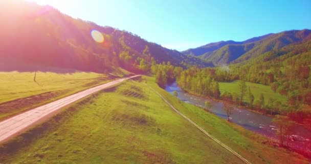 Mid air flygning över färska berg flod och äng på solig sommarmorgon. Landsbygdsvägen nedanför. — Stockvideo