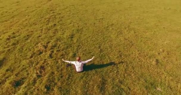 Lage baanvlucht rond mens op groen gras met notitieblok op geel landelijk veld. — Stockvideo