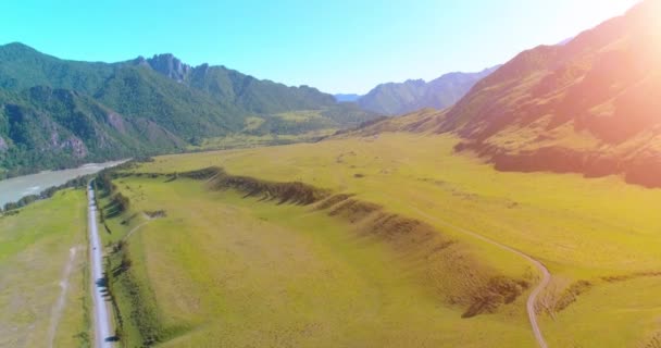 Route de montagne rurale aérienne et prairie au matin ensoleillé d'été. Asphalte autoroute et rivière. — Video