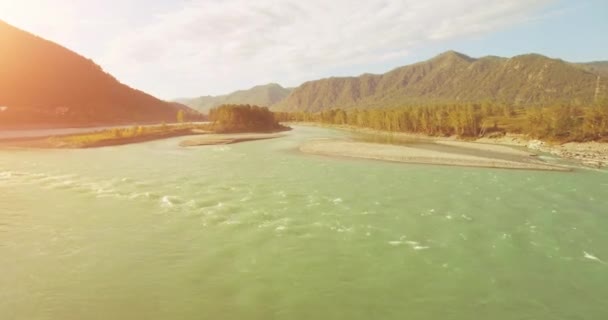 4k UHD hava görüntüsü. Güneşli yaz sabahında taze soğuk dağ nehri üzerinde alçak uçuş. Horisont 'ta yeşil ağaçlar ve güneş ışınları — Stok video