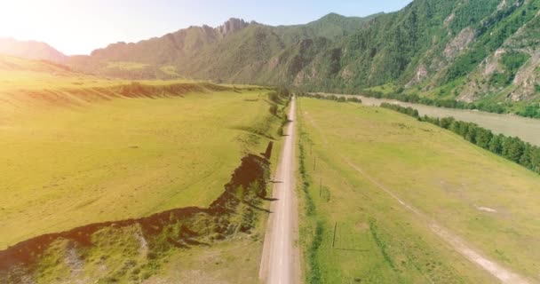 Luftlinie ländliche Bergstraße und Wiese an einem sonnigen Sommermorgen. Asphaltstraße und Fluss. — Stockvideo