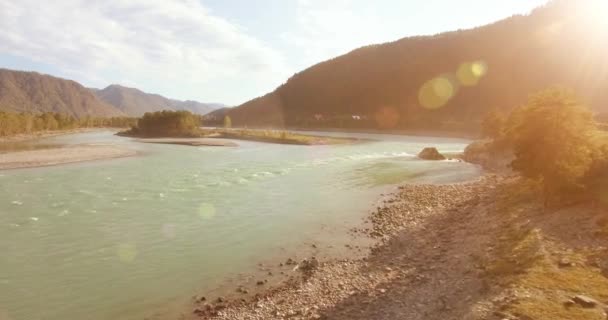 Vol à basse altitude au-dessus d'une rivière de montagne fraîche et rapide avec des rochers au soleil matin d'été. — Video