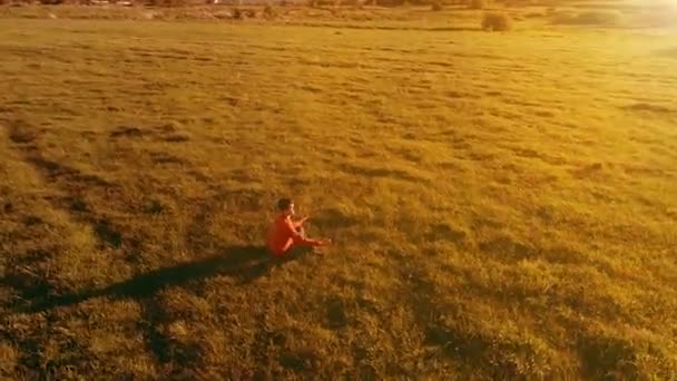 Низкая высота радиального полета над человеком спортивной йоги на идеальной зеленой траве. Закат в горах. — стоковое видео