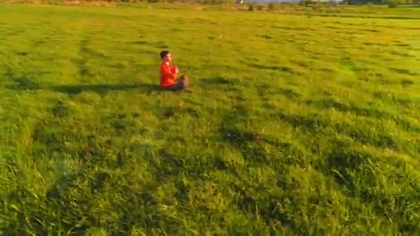 Lage hoogte radiale vlucht over sport yoga man op perfect groen gras. Zonsondergang in de bergen. — Stockvideo