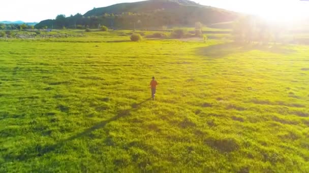 Überflug des Sportlers auf einer grünen Wiese. Sonnenuntergang in den Bergen — Stockvideo
