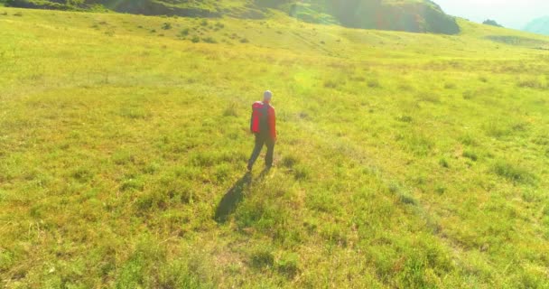 Flight over Backpack hiking tourist walking across green mountain field. Huge rural valley at summer day. — Stock Video