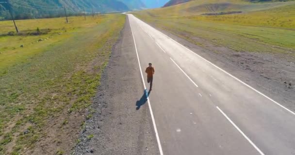 Lage hoogte vlucht voor sportieve man op perfecte asfaltweg — Stockvideo