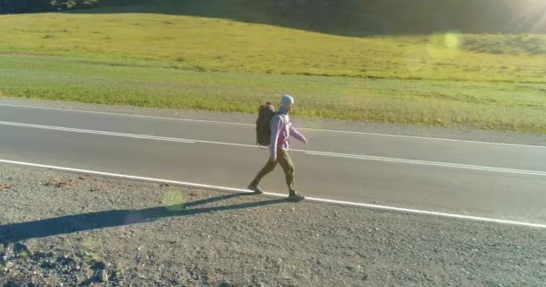 Flyg över liftare turist promenader på asfalterad väg. Enorm lantlig dal på sommardagen. Ryggsäck vandring kille. — Stockvideo