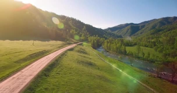 Güneşli yaz sabahında taze dağ nehri ve çayır üzerinde uçuşun ortasında. Aşağıdaki kırsal toprak yol. — Stok video