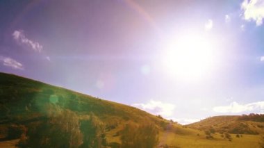 Yazın 4K UHD dağ çayırı zaman dilimi. Bulutlar, ağaçlar, yeşil çimenler ve güneş ışınları hareketi.