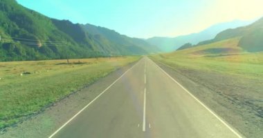 Güneşli yaz sabahında dağ yolu ve çayır üzerinde alçak hava uçuşları..