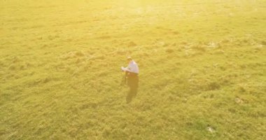 UHD 4k havadan görünümü. Defter pad ile yeşil çim sahasında oturan işadamı üzerinde düşük yörünge uçuş