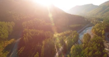Güneşli yaz sabahında taze dağ nehri ve çayır üzerinde uçuşun ortasında. Aşağıdaki kırsal toprak yol.