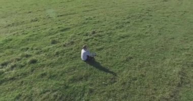 Yeşil çimlerin üzerinde sarı kırsal alanda not defteri olan bir adamın etrafında alçak yörünge uçuşları..