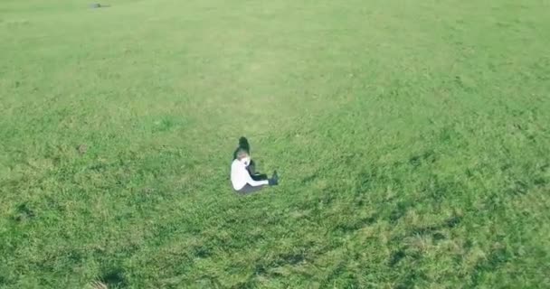 Vol orbital bas autour de l'homme sur herbe verte avec bloc-notes au champ rural jaune. — Video