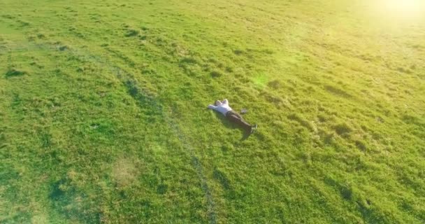 Lage baanvlucht rond mens op groen gras met notitieblok op geel landelijk veld. — Stockvideo